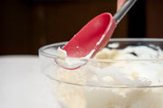 Glass bowl with whipped cream and Cuisipro red Silicone Spoon